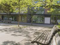 benches in front of a building with trees on it and glass doors to a building