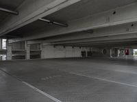 a dark parking garage filled with concrete pillars and ramps and walls and lots of other empty space