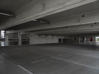 a dark parking garage filled with concrete pillars and ramps and walls and lots of other empty space