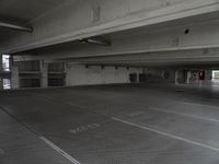 a dark parking garage filled with concrete pillars and ramps and walls and lots of other empty space