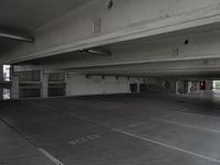 a dark parking garage filled with concrete pillars and ramps and walls and lots of other empty space