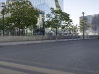 an empty street with a large building in the background on a clear day with trees in the foreground