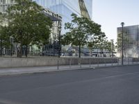 an empty street with a large building in the background on a clear day with trees in the foreground