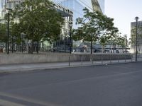 an empty street with a large building in the background on a clear day with trees in the foreground