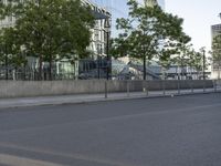 an empty street with a large building in the background on a clear day with trees in the foreground