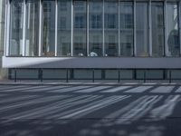 a woman on a scooter walks past a large window display of glass and a building