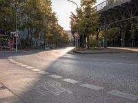 the crosswalk at the street with cars parked on the road below and a bridge overhead