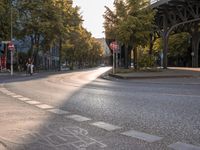 the crosswalk at the street with cars parked on the road below and a bridge overhead