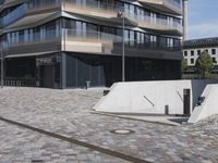 a brick building with glass windows and sidewalk leading to it and a black fire hydrant