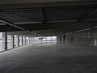 a large empty parking space with lots of windows and grates on the ground inside a building