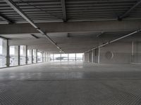 a large empty parking space with lots of windows and grates on the ground inside a building