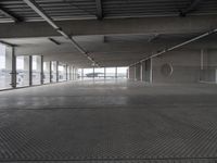 a large empty parking space with lots of windows and grates on the ground inside a building