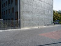 a street and fence are next to a building on which a parking ramp is up