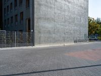 a street and fence are next to a building on which a parking ramp is up