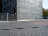 a street and fence are next to a building on which a parking ramp is up