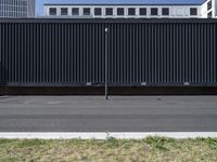 an empty parking lot with black slats and green grass next to the road in front of a large office building