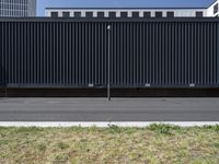 an empty parking lot with black slats and green grass next to the road in front of a large office building