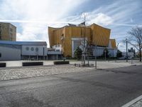 a street with cars parked on the side of it near a large yellow building and a few trees