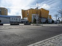 a street with cars parked on the side of it near a large yellow building and a few trees