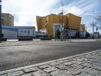 a street with cars parked on the side of it near a large yellow building and a few trees