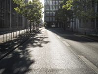 an empty street with trees on each side, and a tall building in the distance