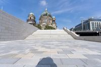 a shadow on the ground with a building behind it and buildings behind it with steeple steps going up to them