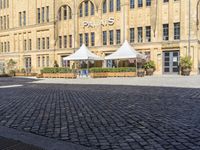 a city square has some umbrellas on the side of it and people are sitting on benches