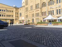 a city square has some umbrellas on the side of it and people are sitting on benches