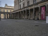 stone path in courtyard with pillars in the building beside it and sign that reads musees du crec between columns