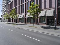 a paved city street and a brick building on the other side of it has awnings