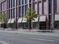 a paved city street and a brick building on the other side of it has awnings