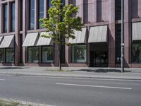 a paved city street and a brick building on the other side of it has awnings