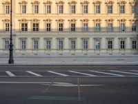 the crosswalk has painted markings on it, with the large buildings in the background