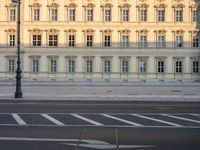 the crosswalk has painted markings on it, with the large buildings in the background