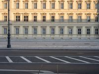 the crosswalk has painted markings on it, with the large buildings in the background