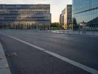 an empty city street lined with tall buildings and a fenced in parking lot to the side