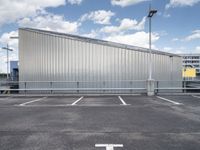 a metal building sitting in the middle of a parking lot near some poles and other traffic