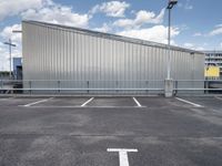 a metal building sitting in the middle of a parking lot near some poles and other traffic