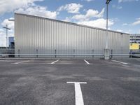 a metal building sitting in the middle of a parking lot near some poles and other traffic