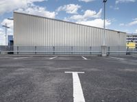 a metal building sitting in the middle of a parking lot near some poles and other traffic