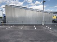 a metal building sitting in the middle of a parking lot near some poles and other traffic