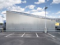 a metal building sitting in the middle of a parking lot near some poles and other traffic