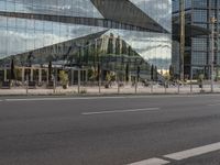 a city street that has a glass building near by it's reflection in the windows