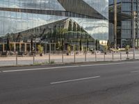 a city street that has a glass building near by it's reflection in the windows