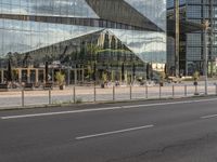 a city street that has a glass building near by it's reflection in the windows