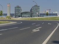 the street with two cars is empty in front of some city buildings by water in a sunny day