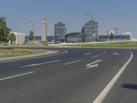 the street with two cars is empty in front of some city buildings by water in a sunny day