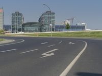 the street with two cars is empty in front of some city buildings by water in a sunny day