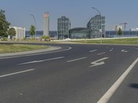 the street with two cars is empty in front of some city buildings by water in a sunny day