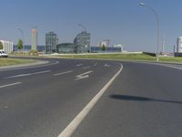 the street with two cars is empty in front of some city buildings by water in a sunny day